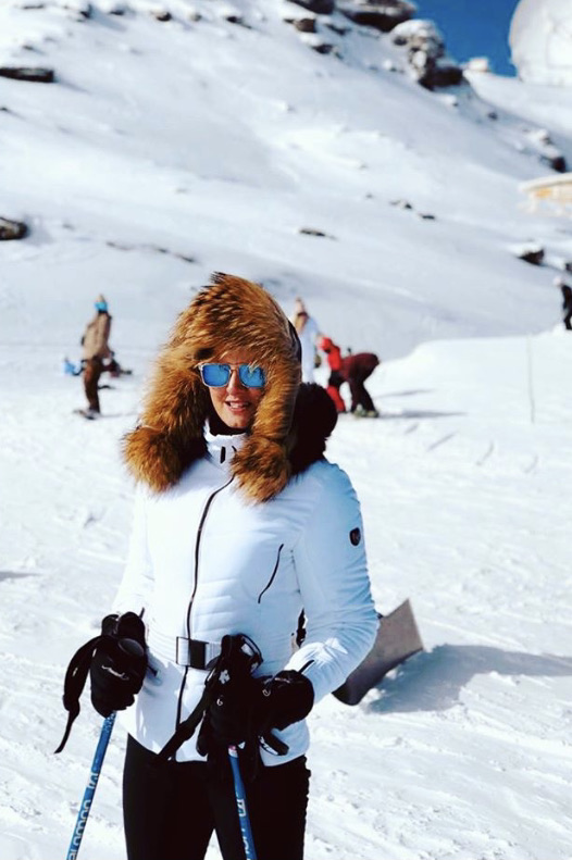 woman wearing bomber ushanka with raccoon fur and pom-poms