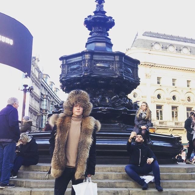 man wearing full fur raccoon ushanka hat in Piccadilly Circus, London