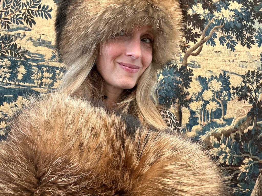 man wearing Russian raccoon fur hat and holding matching muff